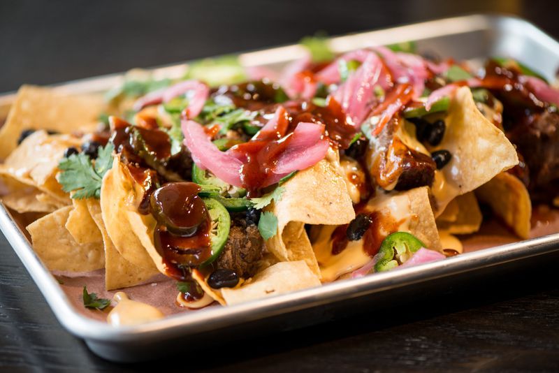  BBQ Nachos, chips and cheese covered with brisket, jalapenos, pickled onions, black beans, cilantro, and BBQ sauce. Photo credit- Mia Yakel.