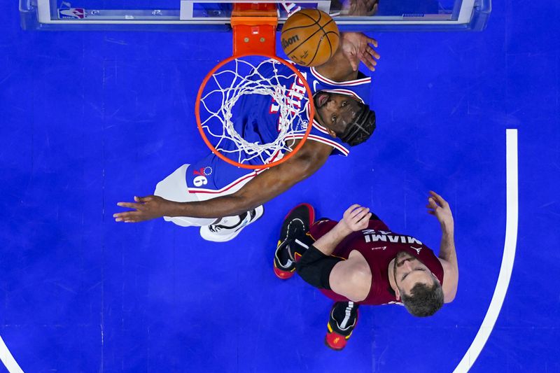 Philadelphia 76ers' Joel Embiid, left, shoots over Miami Heat's Kevin Love during the first half of an NBA basketball play-in tournament game Wednesday, April 17, 2024, in Philadelphia. (AP Photo/Chris Szagola)