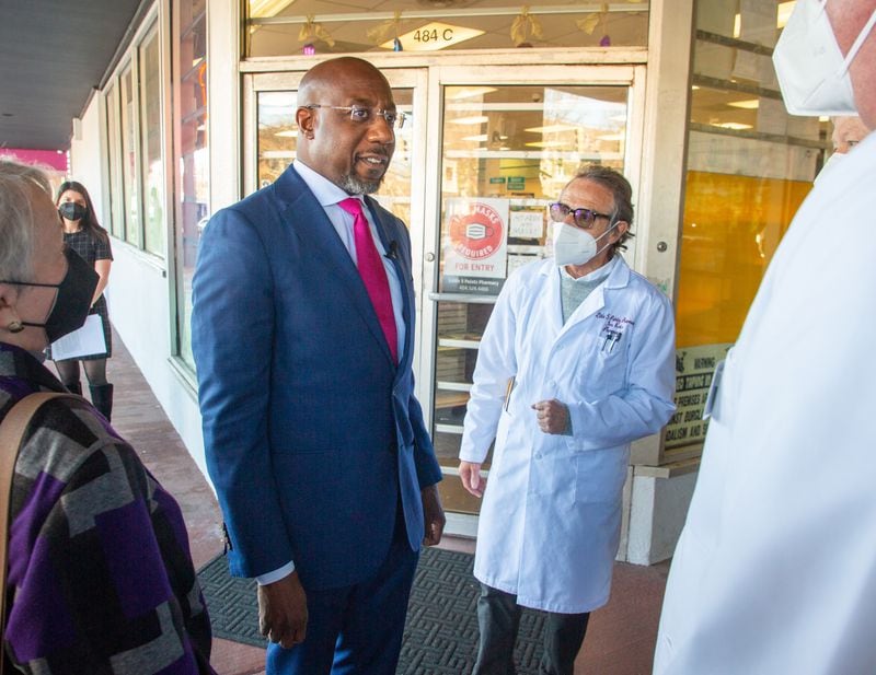 Democratic U.S. Sen. Raphael Warnock, shown talking to pharmacist Ira Katz at the Little Five Points Pharmacy, has campaigned lately by talking more about fighting inflation and lowering the cost of fuel and insulin.   STEVE SCHAEFER FOR THE ATLANTA JOURNAL-CONSTITUTION