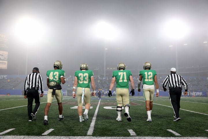 Fog fills the sky as BufordÕs Malik Spencer (43), Nate Norys (33), Jackson Favors (71) and Ashton Daniels (12) walk out for the coin toss against Langston Hughes in the Class 6A state title football game at Georgia State Center Parc Stadium Friday, December 10, 2021, Atlanta. JASON GETZ FOR THE ATLANTA JOURNAL-CONSTITUTION