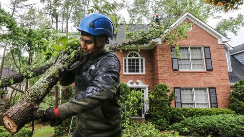 Brandon Mazarie of Castor Tree Service brings out sawed limbs as his crew removed a tree from a house on Forest Crossing Drive on Monday after severe storms passed through the metro area.
