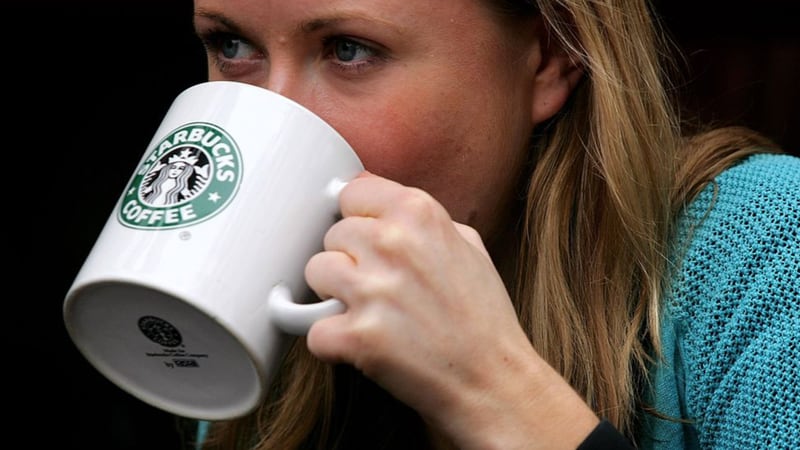 FILE PHOTO: A woman drinks from a coffee mug in A Starbucks store in central London on April 25, 2006 in London, England.