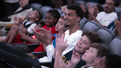 San Antonio Spurs' Victor Wembanyama, center, watches videos with local children before receiving his 2023-24 NBA Rookie of the Year trophy, Saturday, May 11, 2024, in San Antonio. (AP Photo/Darren Abate)