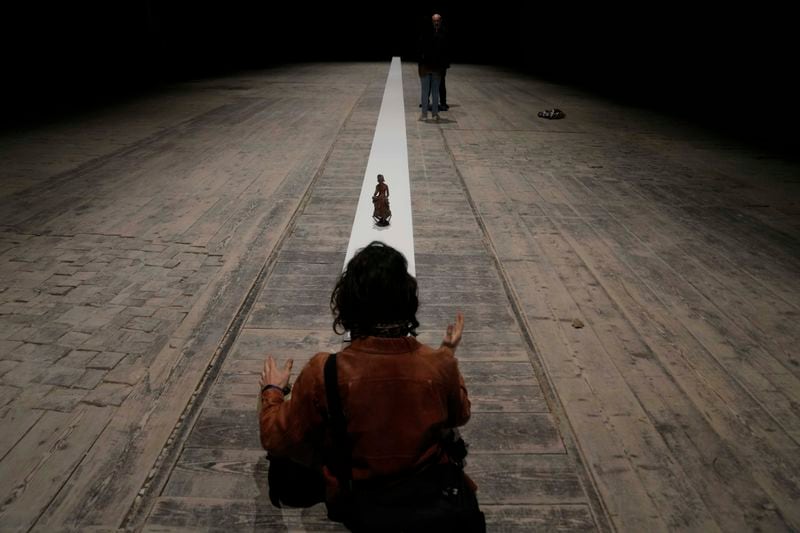 A visitor gestures as he sits in front of he installation 'Due qui to hear' by artist Massimo Bartolini at the Italian pavilion at the 60th Biennale of Arts exhibition in Venice, Italy, Tuesday, April 16, 2024. The Venice Biennale contemporary art exhibition opens Saturday for its six-month run through Nov. 26. The main show titled 'Stranieri Ovunque – Foreigners Everywhere' is curated for the first time by a Latin American, Brazilian Adrian Pedrosa. Pedrosa is putting a focus on underrepresented artists from the global south, along with gay and Indigenous artists. Alongside the main exhibition, 88 national pavilions fan out from the traditional venue in Venice's Giardini, to the Arsenale and other locations scattered throughout the lagoon city. (AP Photo/Luca Bruno)