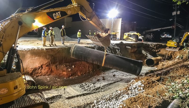 Crews have lowered a new  main into the ground at the site of the massive water main break in DeKalb County. JOHN SPINK / JSPINK@AJC.COM