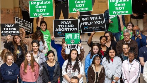 Supporters of abortion rights and anti-abortion activists hold opposing signs at a February anti-abortion rally at the Georgia Capitol in Atlanta. (Arvin Temkar / arvin.temkar@ajc.com)