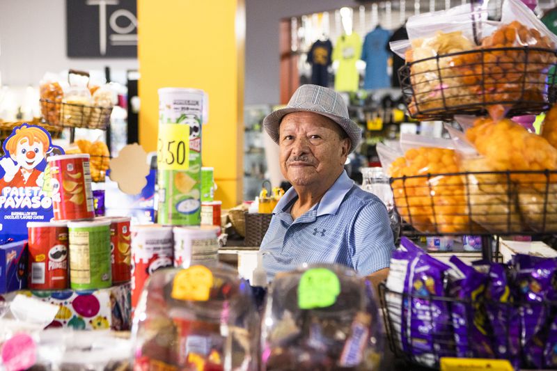 Juan Patiño sits behind the counter of his shop Soy Garapiñados, where he sells snack foods. CHRISTINA MATACOTTA FOR THE ATLANTA JOURNAL-CONSTITUTION.