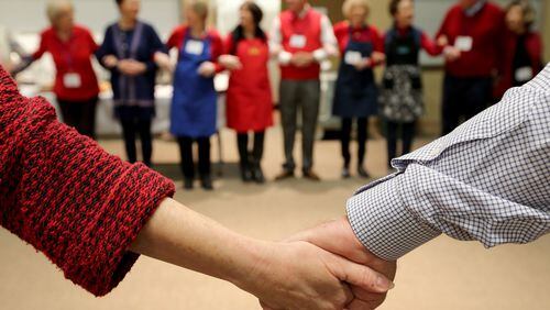Participants join hands at a job networking event in Roswell last year. (Ben Gray / bgray@ajc.com)
