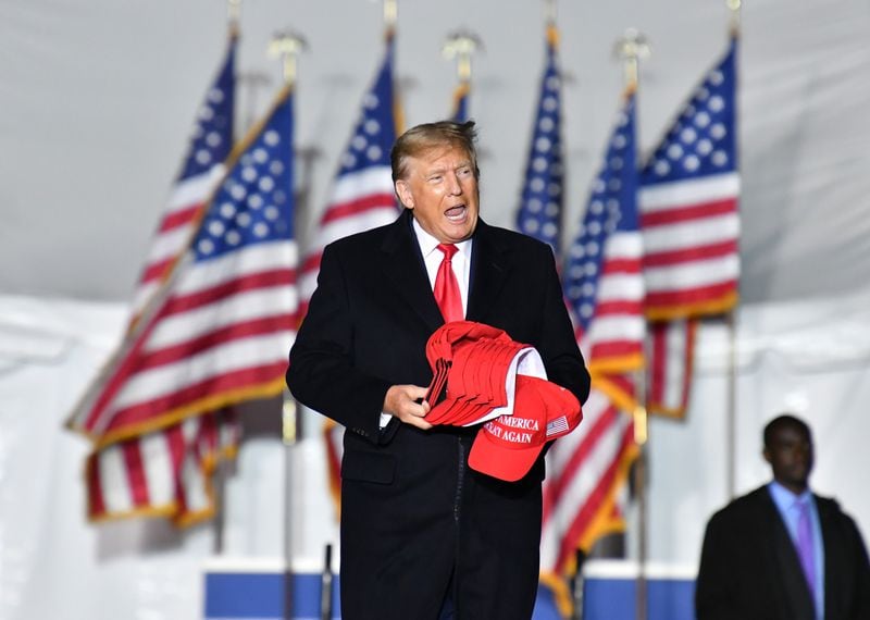 March 26, 2022 Commerce - Former former President Donald Trump enters the stage with his hats during a rally for Georgia GOP candidates at Banks County Dragway in Commerce on Saturday, March 26, 2022. (Hyosub Shin / Hyosub.Shin@ajc.com)
