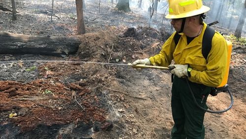 David Jordan, park manager, uses a backpack-mounted water cannon to soak hot spots in a brush fire at Sweetwater Creek State Park. Photo: Bo Emerson