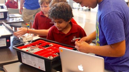 A junior from Holy Innocents' Upper School works with a kindergartner from the Primary School inside of a STEM robotics lab. Holy Innocents' Episcopal School is hosting its "STEMsational" camp on Saturday, Nov. 5.