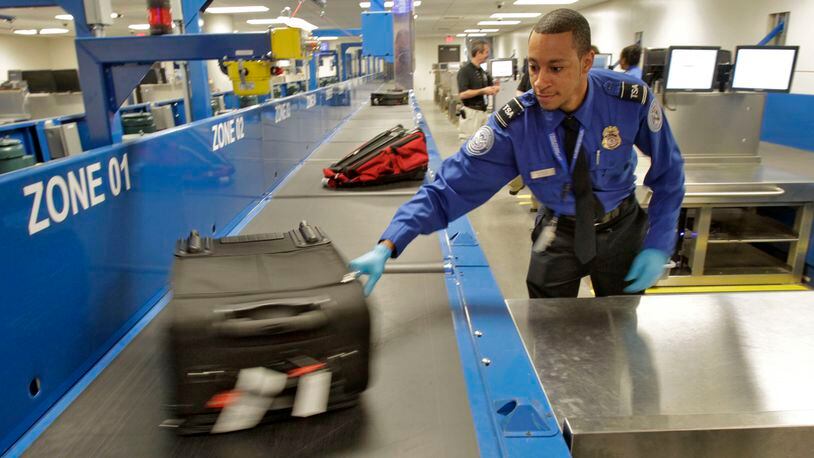 An officer in Hartsfield-Jackson’s baggage inspection room pulls a bag that was flagged for a physical check. A project for a new system at the world’s busiest airport has generated a contracting dispute. Bob Andres bandres@ajc.com