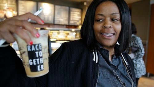 Larenda Myres holds an iced coffee drink with a "Race Together" sticker on it at a Starbucks store in Seattle, Wednesday, March 18, 2015.