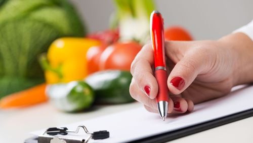 Nutritionist writing medical records and prescriptions with fresh vegetables. (Andrea De Martin/Dreamstime/TNS)