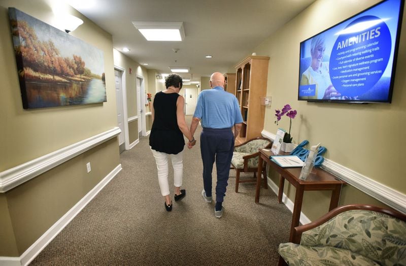 Karen J. Hardwick and her husband, Greg, who has Alzheimer’s disease, hold hands as they return to his room at Addington Place at the Mills in Roswell recently. Greg’s younger brother Scott also battled Alzheimer’s. HYOSUB SHIN / HYOSUB.SHIN@AJC.COM