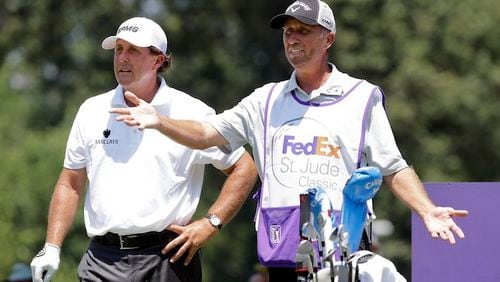 FILE - In this June 11, 2015, file photo, Phil Mickelson, left, talks with his caddie Jim Mackay on the eighth tee during the first round of the St. Jude Classic golf tournament in Memphis, Tenn. Mickelson and his caddie have decided to part ways after 25 years of one of the most famous player-caddie relationships on the PGA Tour. Mickelson and Jim "Bones" Mackay say the decision to split was mutual and not based on an incident. (AP Photo/Mark Humphrey, File)