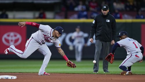 Atlanta Braves shortstop Orlando Arcia, left, misses fielding the ball but second baseman Ozzie Albies (1) is able to make the stop and throw to first base for the out against Seattle Mariners' Ty France during the sixth inning of a baseball game Tuesday, April 30, 2024, in Seattle. (AP Photo/Lindsey Wasson)
