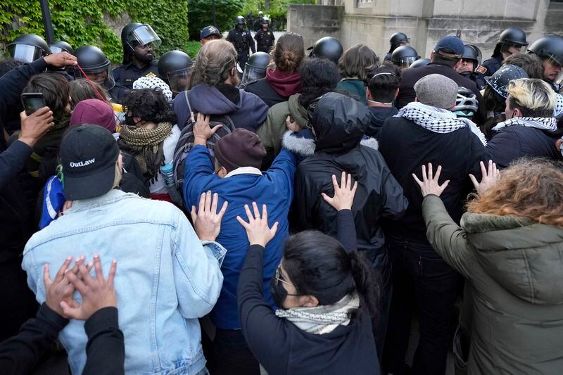 Pro-Palestinian protesters support the positions held by others as University of Chicago police officers reposition a barricade keeping protesters from the university's quad while the student encampment is dismantled Tuesday, May 7, 2024, in Chicago. (AP Photo/Charles Rex Arbogast)