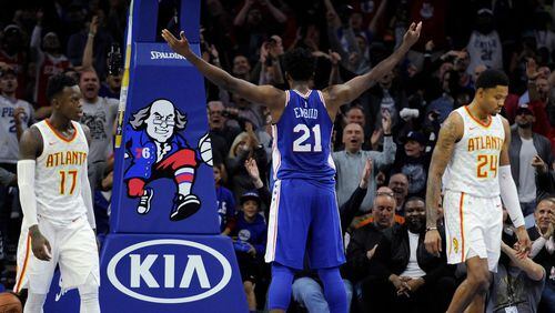 Philadelphia 76ers' Joel Embiid (21) gestures to the crowd as Atlanta Hawks' Dennis Schroder (17) and Kent Bazemore (24) walk off the court during the second half of an NBA basketball game, Wednesday, Nov. 1, 2017, in Philadelphia. The 76ers won 119-107. (AP Photo/Michael Perez)