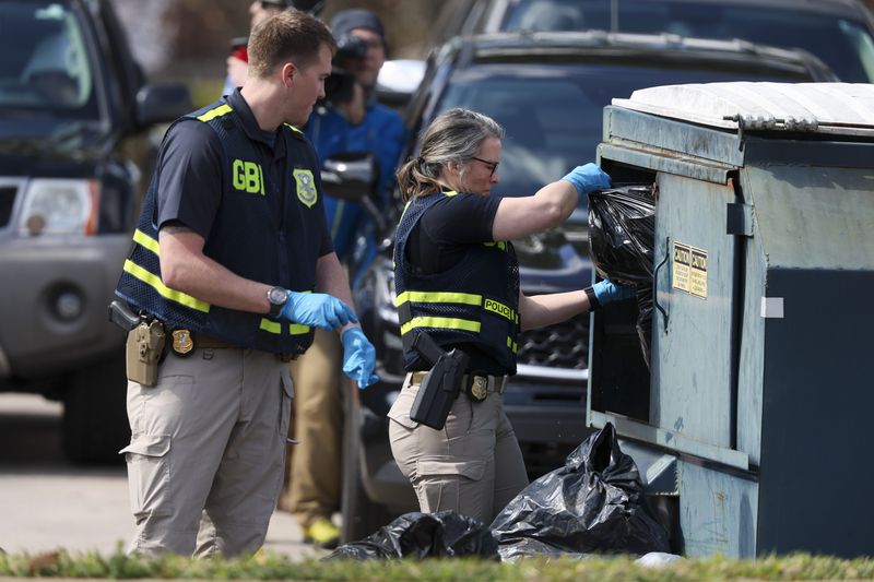 GBI officers search a dumpster across the street from the Cielo Azulak Apartments, Friday, Feb. 23, 2024, in Athens, Ga. (Jason Getz / jason.getz@ajc.com)