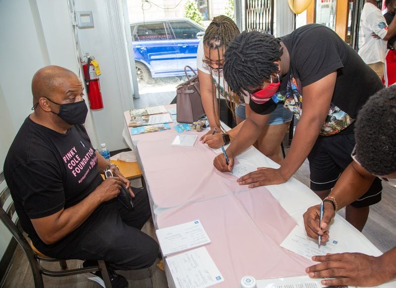 John Saunders watches as Tierra Hall (left) and Johnny Jones sign up for life insurance during an event at Big Dave's Cheesesteaks in downtown Atlanta. PHIL SKINNER FOR THE ATLANTA JOURNAL-CONSTITUTION