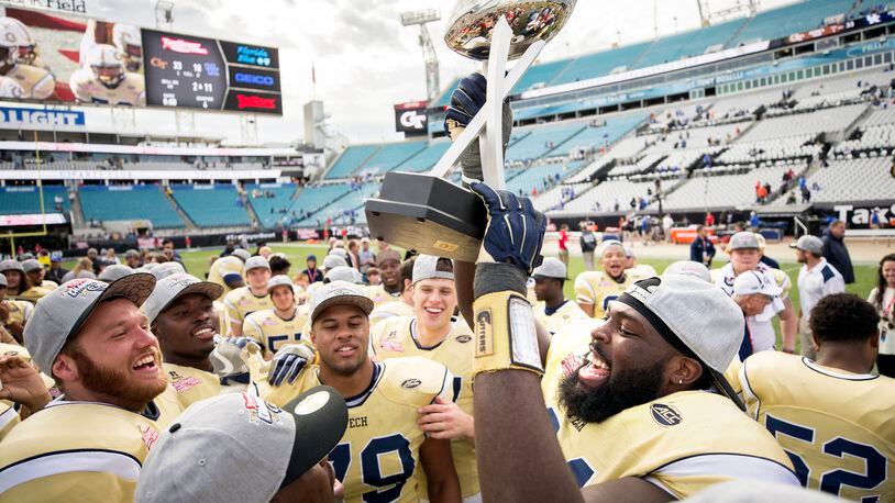 Georgia Tech defensive lineman Patrick Gamble (91) and his team mates celebrate with the trophy after the TaxSlayer Bowl NCAA college football game against Kentucky, Saturday, Dec. 31, 2016, in Jacksonville, Fla. Georgia Tech beat Kentucky 33-18. (AP Photo/Stephen B. Morton)