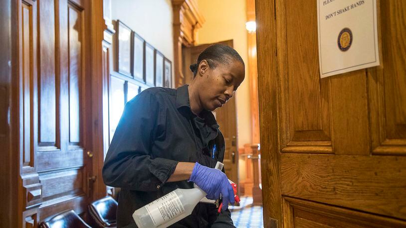Custodian Brenda Love cleans the door handles at the Georgia Capitol earlier this month. Love said she cleaned “everything the public touches” out of caution due to the coronavirus. (ALYSSA POINTER/ALYSSA.POINTER@AJC.COM)