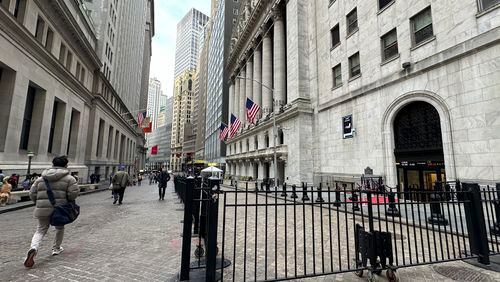 People pass the New York Stock Exchange, right, on Wednesday, April 17, 2024 in New York. Global shares are trading mixed after most U.S. stocks slipped on firmer expectations that the Fed is committed to its current rate practices.(AP Photo/Peter Morgan)