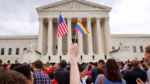 In this June 26, 2015 file photo, a man holds a U.S. and a rainbow flag outside the Supreme Court in Washington after the court legalized gay marriage nationwide. (AP Photo/Jacquelyn Martin)
