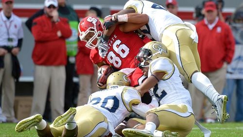 RALEIGH, NC - NOVEMBER 08: Lawrence Austin #20, Demond Smith #12 and Paul Davis #40 of the Georgia Tech Yellow Jackets tackle David Grinnage #86 of the North Carolina State Wolfpack during their game at Carter-Finley Stadium on November 8, 2014 in Raleigh, North Carolina. (Photo by Grant Halverson/Getty Images)