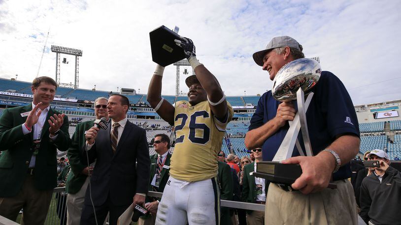JACKSONVILLE, FL - DECEMBER 31: Dedrick Mills #26 of the Georgia Tech Yellow Jackets hoists the TaxSlayer Bowl MVP trophy as head coach Paul Johnson looks on after the game against the Kentucky Wildcats at EverBank Field on December 31, 2016 in Jacksonville, Florida. (Photo by Rob Foldy/Getty Images)