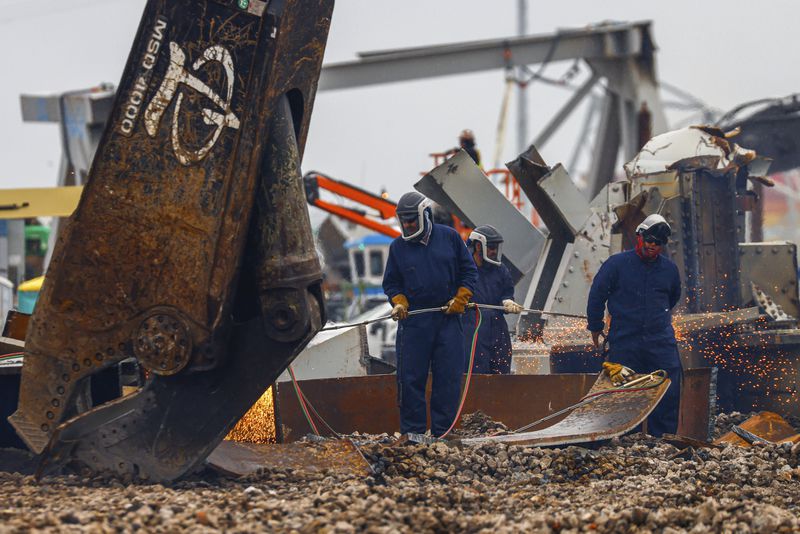 Workers use torches to break apart large salvaged pieces of the collapsed Francis Scott Key Bridge at Tradepoint Atlantic, Friday, April 12, 2024, in Sparrows Point, Md. (AP Photo/Julia Nikhinson)