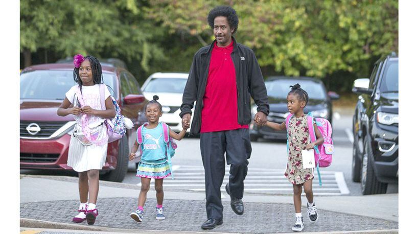 William White IV walks his daughters Allison White (from left), Amber White (second from left) and Ashley White (right) to M. Agnes Jones Elementary School, Atlanta. Milton has awarded a contract to create a smartphone app that would encourage kids to walk to school. AJC FILE / ALYSSA POINTER / ALYSSA.POINTER@AJC.COM