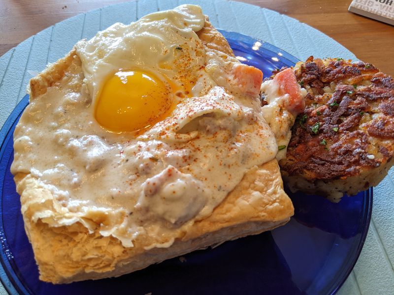 Snooze’s breakfast pot pie features a puff pastry, smothered with rosemary sausage gravy, and topped with a sunny-side-up egg. It is served with a side of hash browns. Courtesy of Paula Pontes