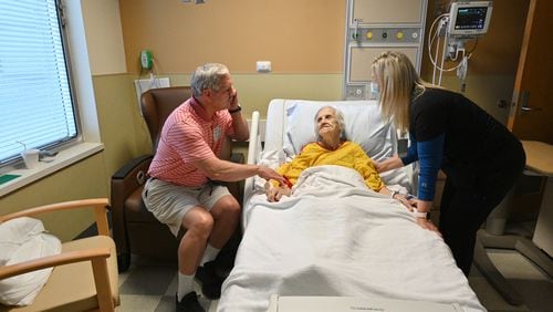 Bill Collins holds the hand of his mother, Edith Collins, as Candice Wade (right), a registered nurse, checks on her at the cardiovascular unit of the Northeast Georgia Medical Center in Gainesville. (Hyosub Shin / Hyosub.Shin@ajc.com)