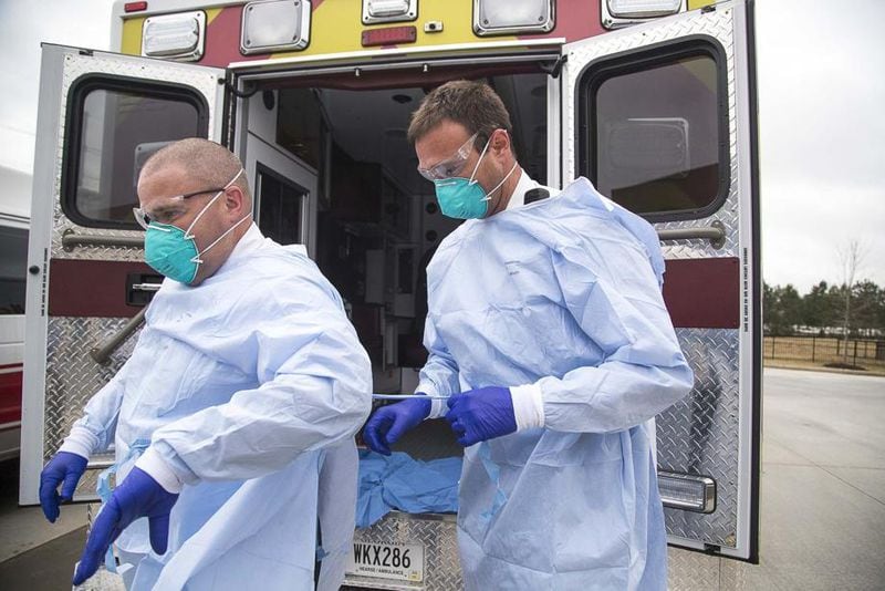 David Beranek (right), operation field supervisor at Metro Atlanta Ambulance Services, assists Anthony Zajac (left), a clinical field supervisor, with his protective gear.
