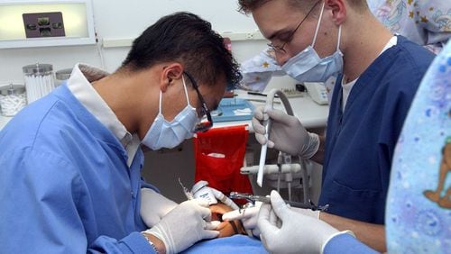 Dr. Thein “Tim” Pham, left, a co-founder of Kool Smiles, is seen working on a filling of a 5-year-old girl in 2002. The company will payout $24 million after a court settlement.