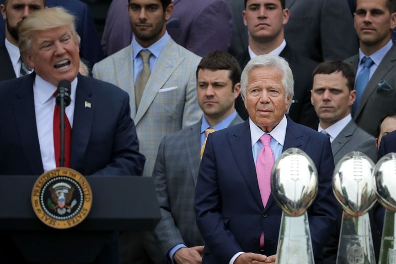 Activists and lawsuits have accused NFL owners of kneeling to President Trump in how they deal with player protests. New England Patriots owner Robert Kraft (C) listens to U.S. President Donald Trump deliver remarks during an event celebrating the team's Super Bowl win on the South Lawn at the White House April 19, 2017 in Washington, DC. It was the team's fifth Super Bowl victory since 1960. (Photo by Chip Somodevilla/Getty Images)