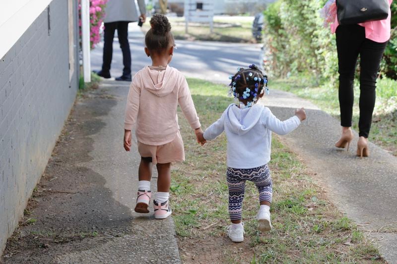 Two children walk hand in hand to the front yard for the opening of Auntie Angie’s.  (Natrice Miller/ natrice.miller@ajc.com)