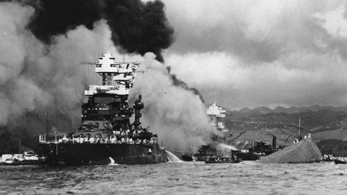 FILE - In this Dec. 7, 1941 file photo, part of the hull of the capsized USS Oklahoma is seen at right as the battleship USS West Virginia, center, begins to sink after suffering heavy damage, while the USS Maryland, left, is still afloat in Pearl Harbor, Oahu, Hawaii. (AP Photo/U.S. Navy, File)