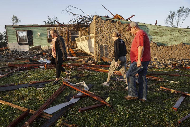 People check a storm damaged home at sunrise Tuesday, May 7, 2024, in Barnsdall, Okla. A tornado destroyed homes, forced the evacuation of a nursing home and toppled trees and power lines when it roared through the small Oklahoma town. (Mike Simons/Tulsa World via AP)