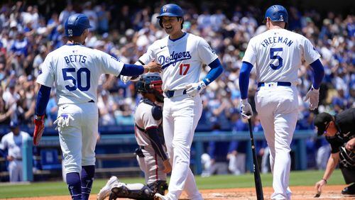 Los Angeles Dodgers designated hitter Shohei Ohtani (17) celebrates with Mookie Betts (50) and Freddie Freeman (5) after hitting a home run during the first inning of a baseball game against the Atlanta Braves in Los Angeles, Sunday, May 5, 2024. Betts also scored. (AP Photo/Ashley Landis)