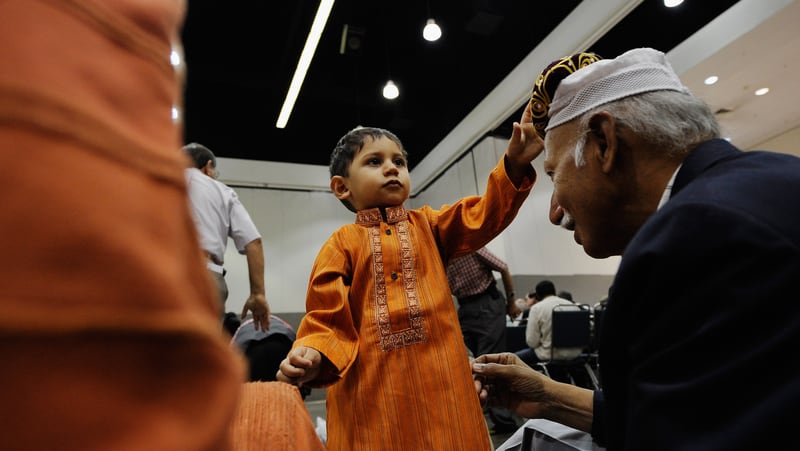 Seventeen months -old Pakistani Muslim Ali Khaja gives his hat to his grandfather Ahsan Khaja before for the special 2011 Eid ul-Fitr morning prayer in Los Angeles, California.