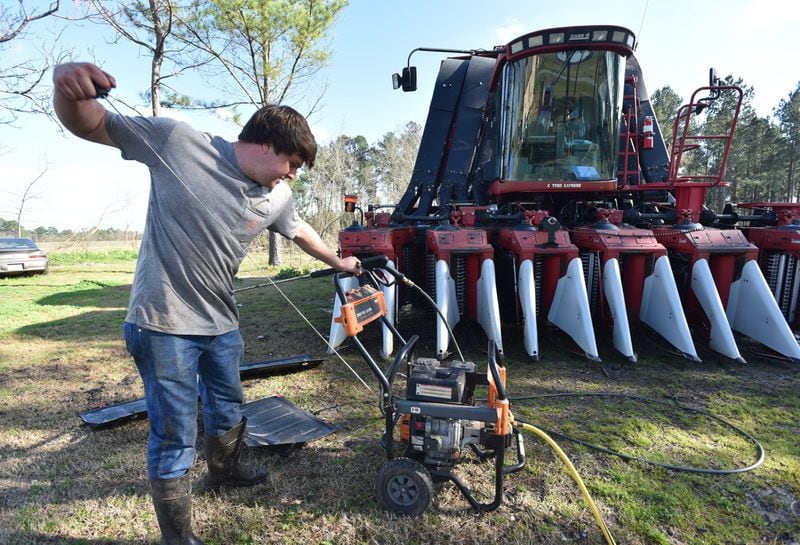 Young farmer Reese Foster prepares to power-wash a gigantic cotton picker at his home near Dawson, Georgia. Foster and many other farmers are carrying over debt into 2019 because bad weather ruined crops. Chinese tariffs are also destabilizing the market for cotton, pecans, peanuts and other Georgia crops, which has a broader economic impact on the state. HYOSUB SHIN / HSHIN@AJC.COM