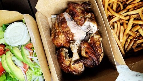The family-style pollo a la brasa from Las Brasas in Decatur includes a Peruvian-spiced rotisserie-cooked chicken (center) with a house salad and a hearty serving of fries.