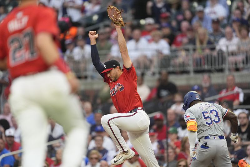 Texas Rangers' Adolis García (53) is forced out at first basere by Atlanta Braves first base Matt Olson (28) after hitting a ground ball in the first inning of a basedball game Friday, April 19, 2024, in Atlanta. (AP Photo/John Bazemore)