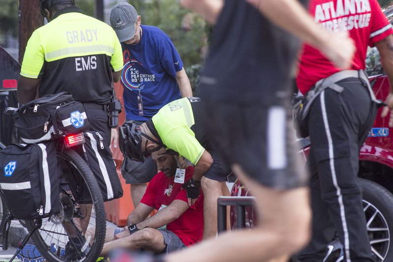 A runner is checked by Grady hospital EMS during the 49th running of the AJC Peachtree road race near Piedmont Park, Wednesday, July 4, 2018.  ALYSSA POINTER/ALYSSA.POINTER@AJC.COM