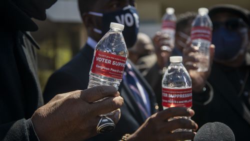 Religious leaders hold bottles of water with labels that read “Voter Suppression” following a press conference in April 2021 outside of the World of Coca-Cola in downtown Atlanta. (Alyssa Pointer / Alyssa.Pointer@ajc.com)