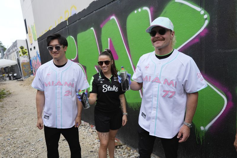 Sauber drivers, Zhou Guanyu of China, left, Valtteri Bottas of Finland, right, and Carrie Schreiner, who represents Sauber in the F1 Academy racing series, pose after getting a graffiti lesson during a visit to the Museum of Graffiti, ahead of the Formula One Miami Grand Prix auto race, Wednesday, May 1, 2024, in Miami. (AP Photo/Rebecca Blackwell)
