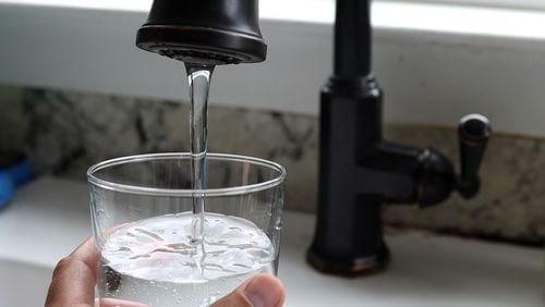 A file photo shows tap water filling a glass. The north Georgia city of Calhoun, which has been home to flooring and carpet manufacturing for decades, is facing multiple lawsuits alleging sewage sludge from its wastewater treatment plant has contaminated land and water in the area with toxic “forever chemicals.” (Justin Sullivan/Getty Images/TNS)